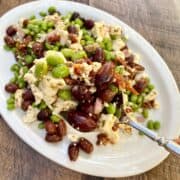 Edamame salad on a plate with a large spoon scooping out a portion of salad.