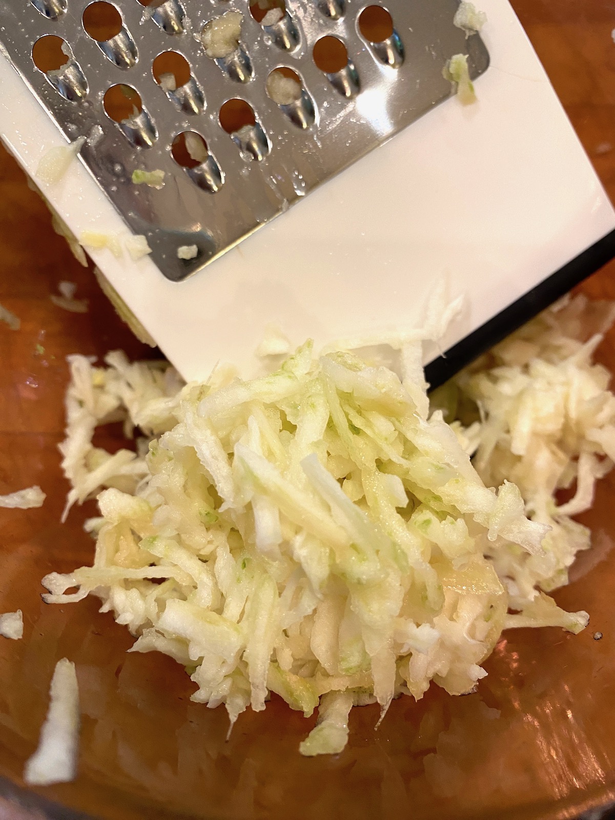 Grated elephant garlic in a bowl with a grater on the side. 