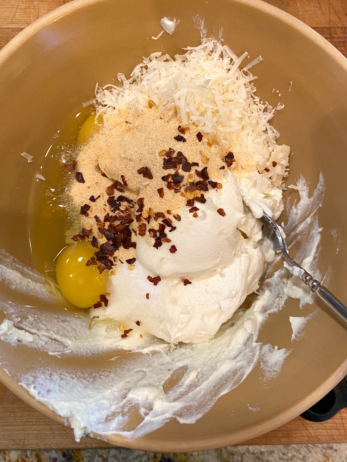 Ricotta cheese, egg, parmesan cheese, garlic powder and red pepper flakes in a bowl. 