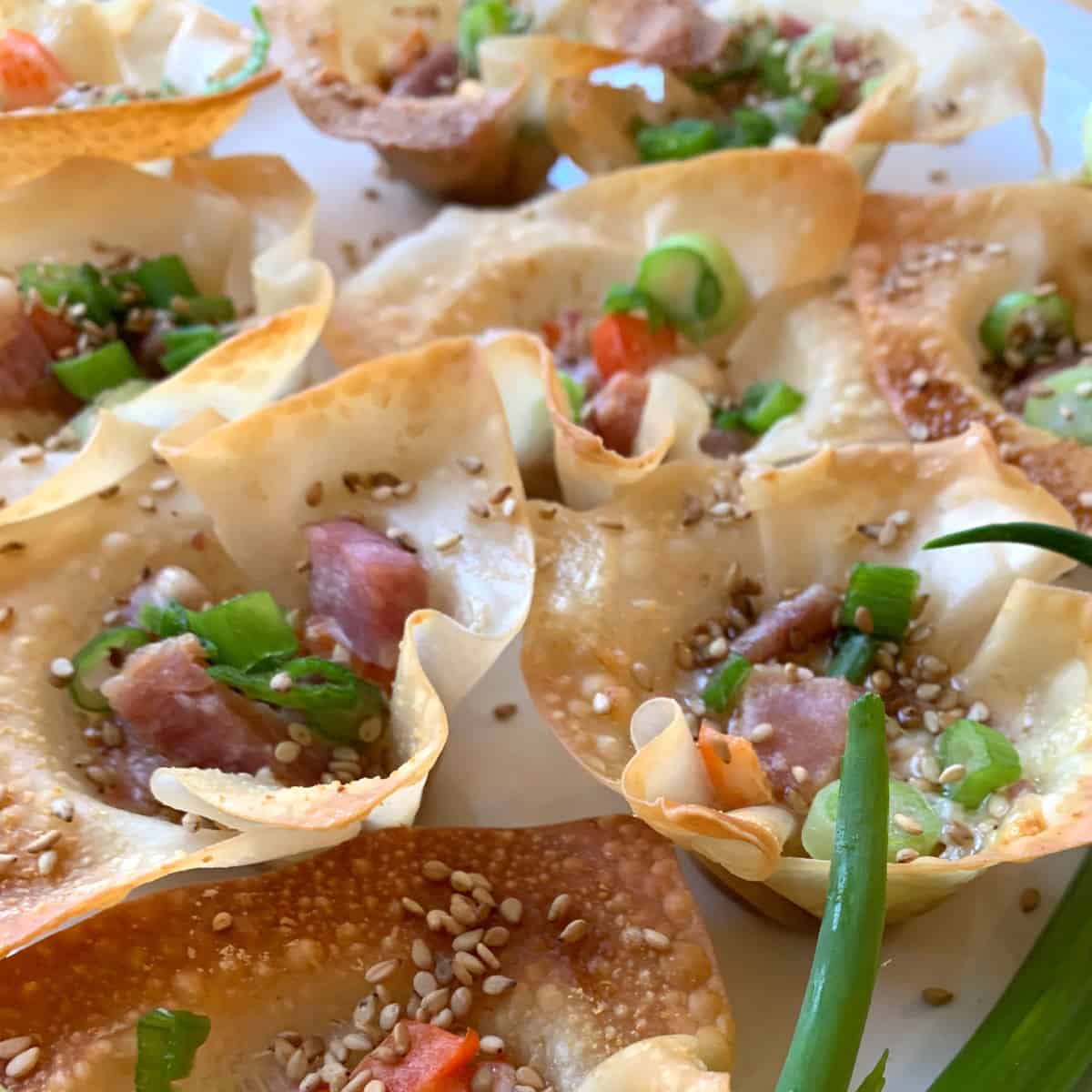 Pork wonton stars arranged on a platter with diced ham and green onions.