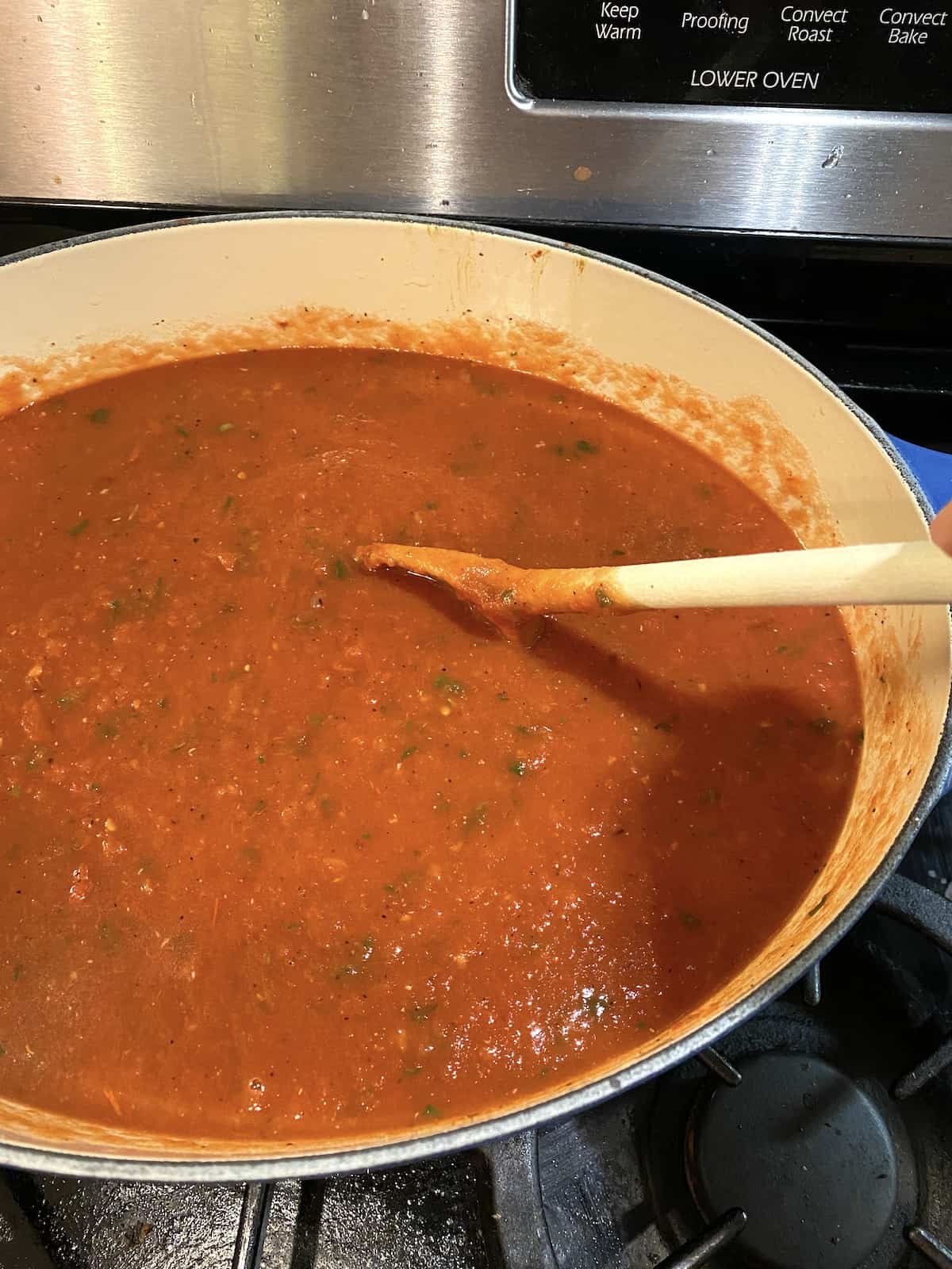 A stock pot on the stove, full of tomato basil soup. 