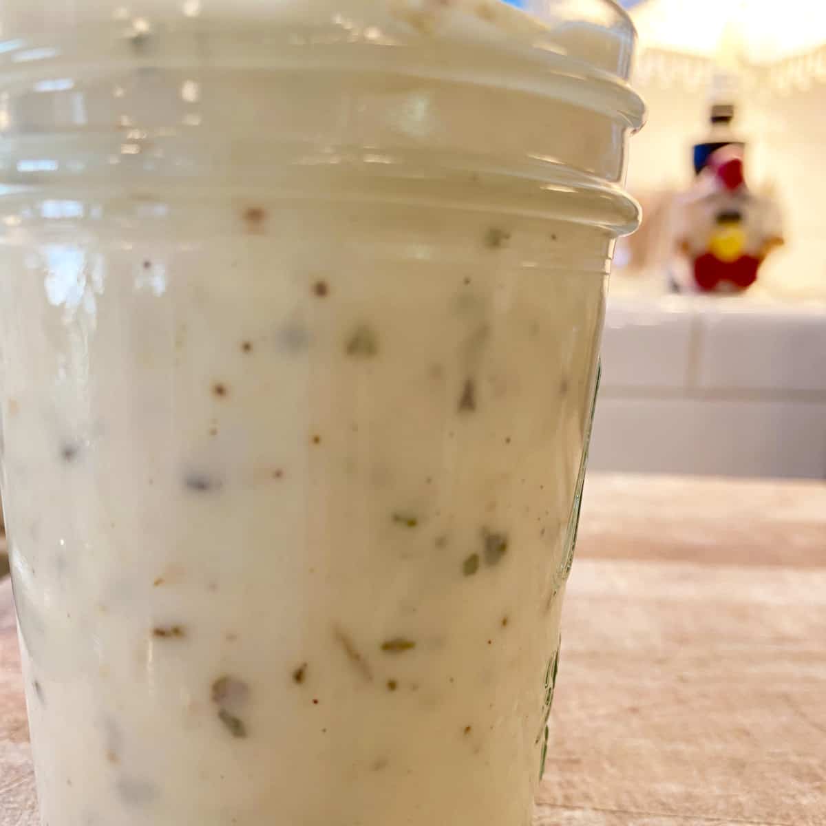 A small jar on a cutting board, full of garlic parmesan white pizza sauce.