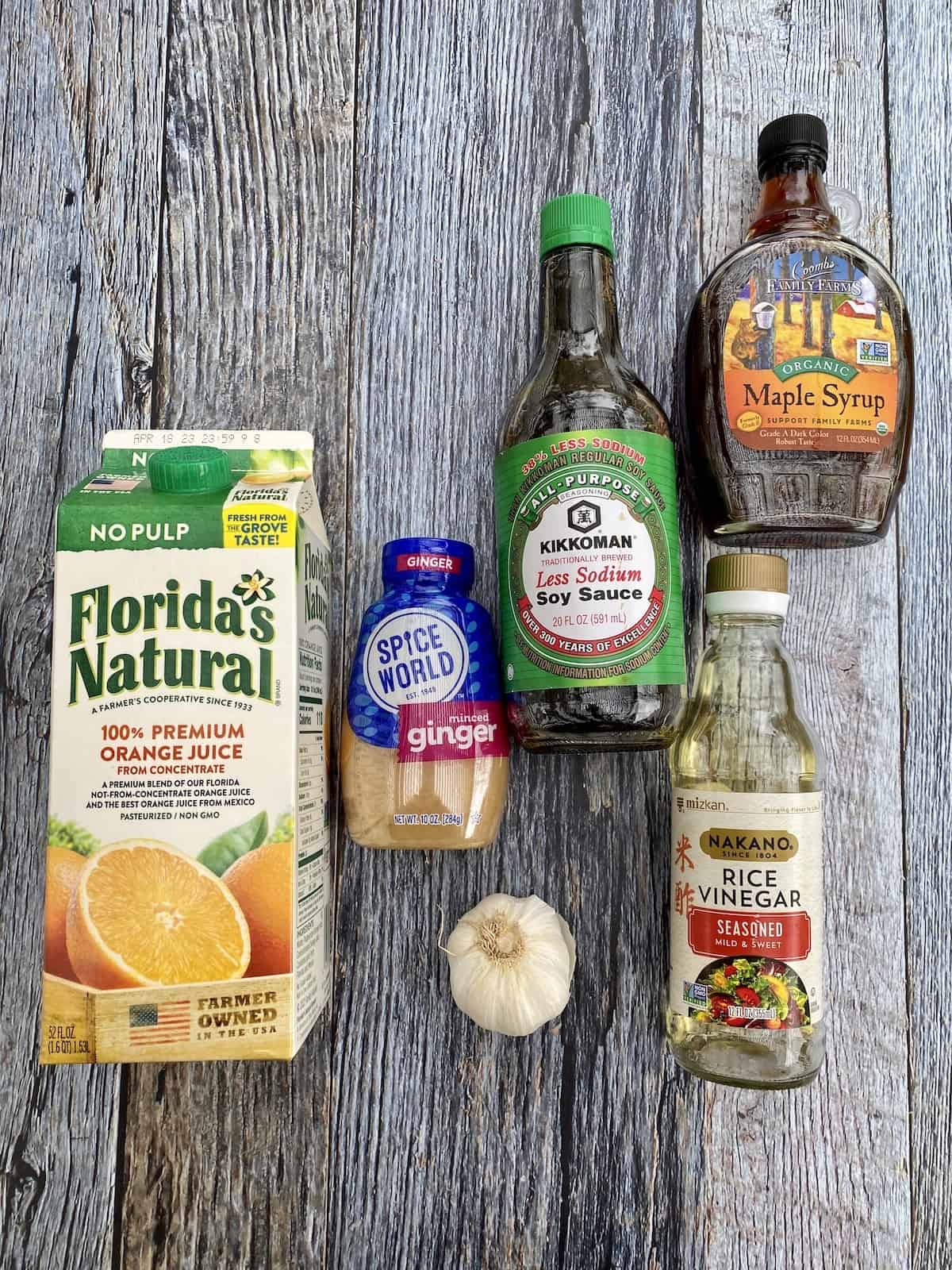 Orange sauce ingredients in their packaging arranged on a wooden plank.