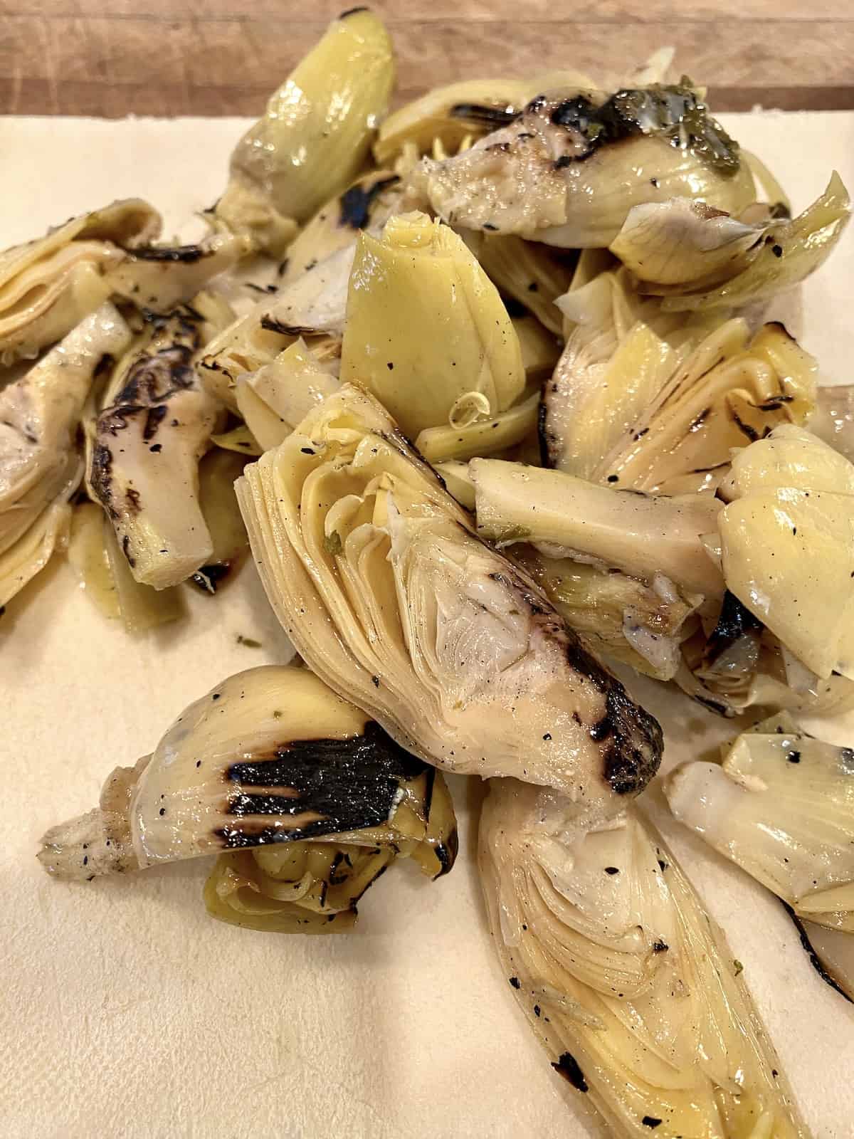 Marinated artichoke hearts on a cutting board.