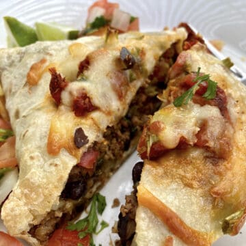 A large beef burrito cut in half on a plate.
