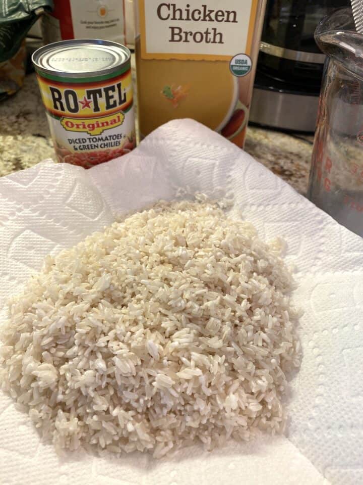 Rice drying a paper towel with canned tomatoes and boxed chicken broth in the background.