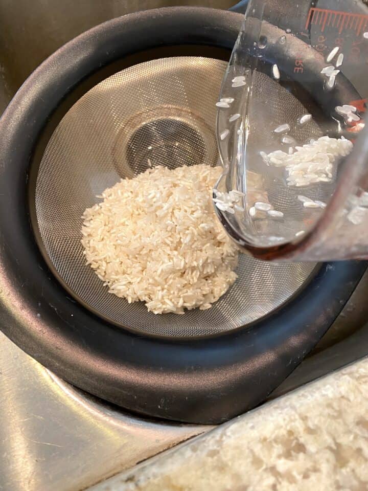 Rice in a strainer over the kitchen sink.