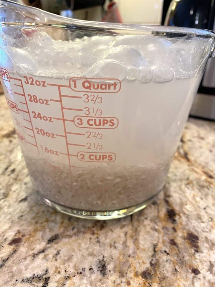 Rice and water in a glass measuring cup.