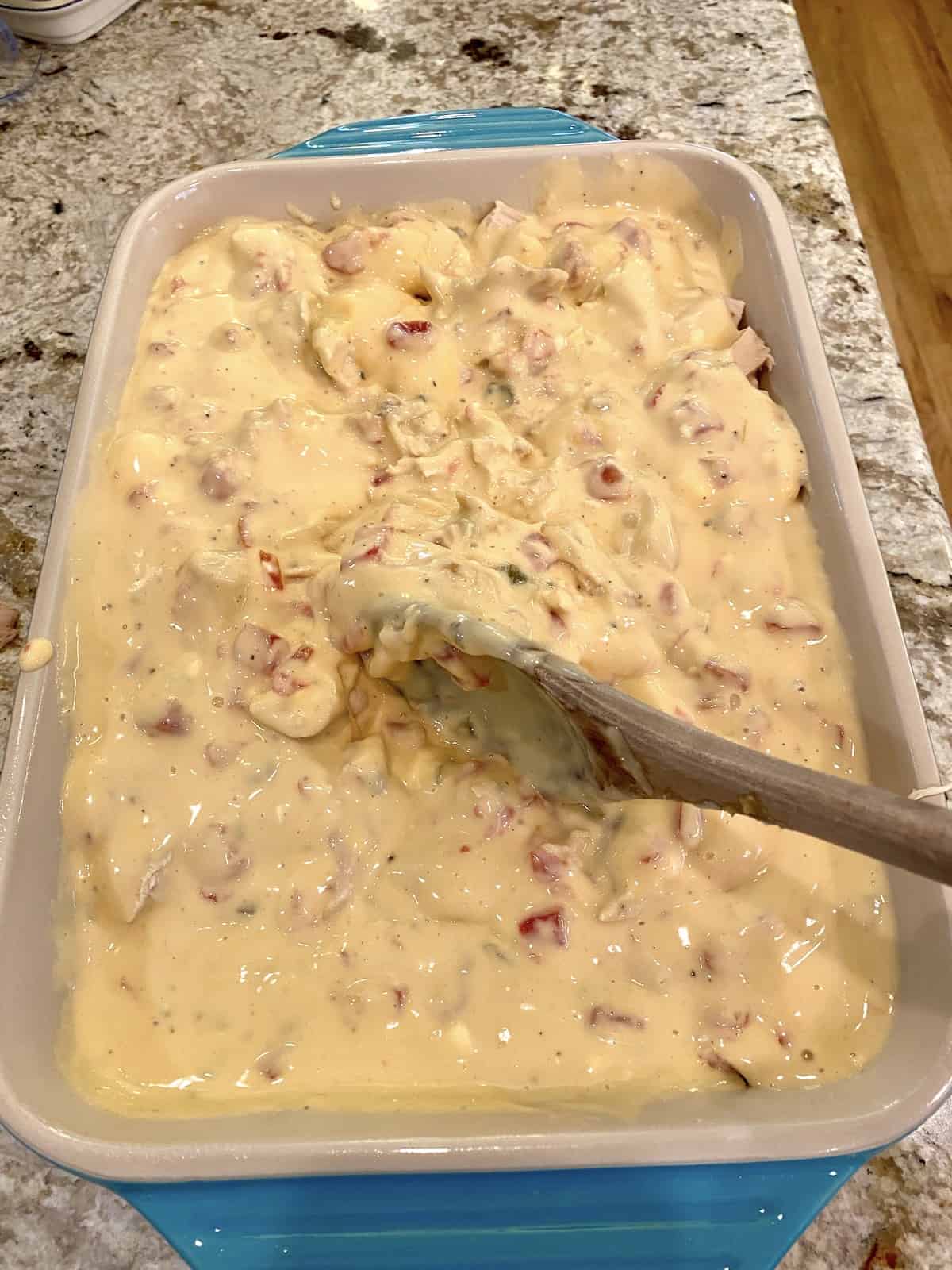 Chicken spaghetti with cheesy sauce on top in a baking dish.