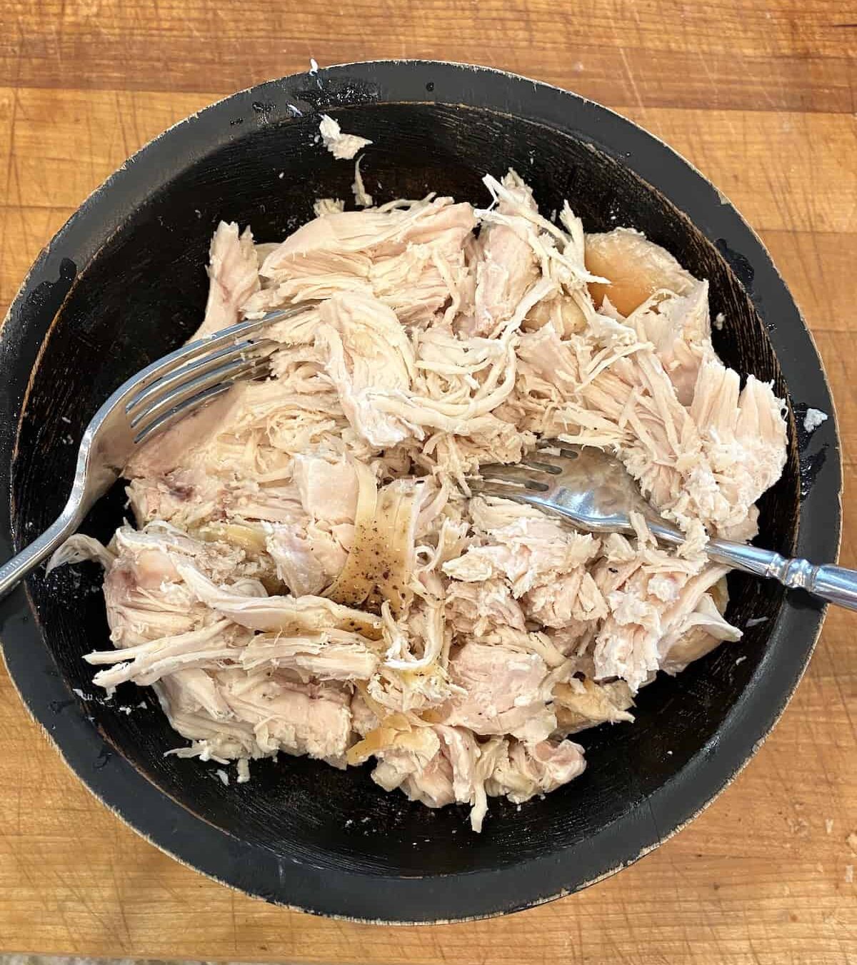 Chicken chicken in a bowl on a cutting board.