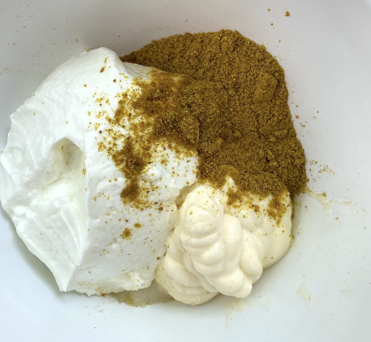 Curry powder on top of mayonnaise and non-fat Greek yogurt.