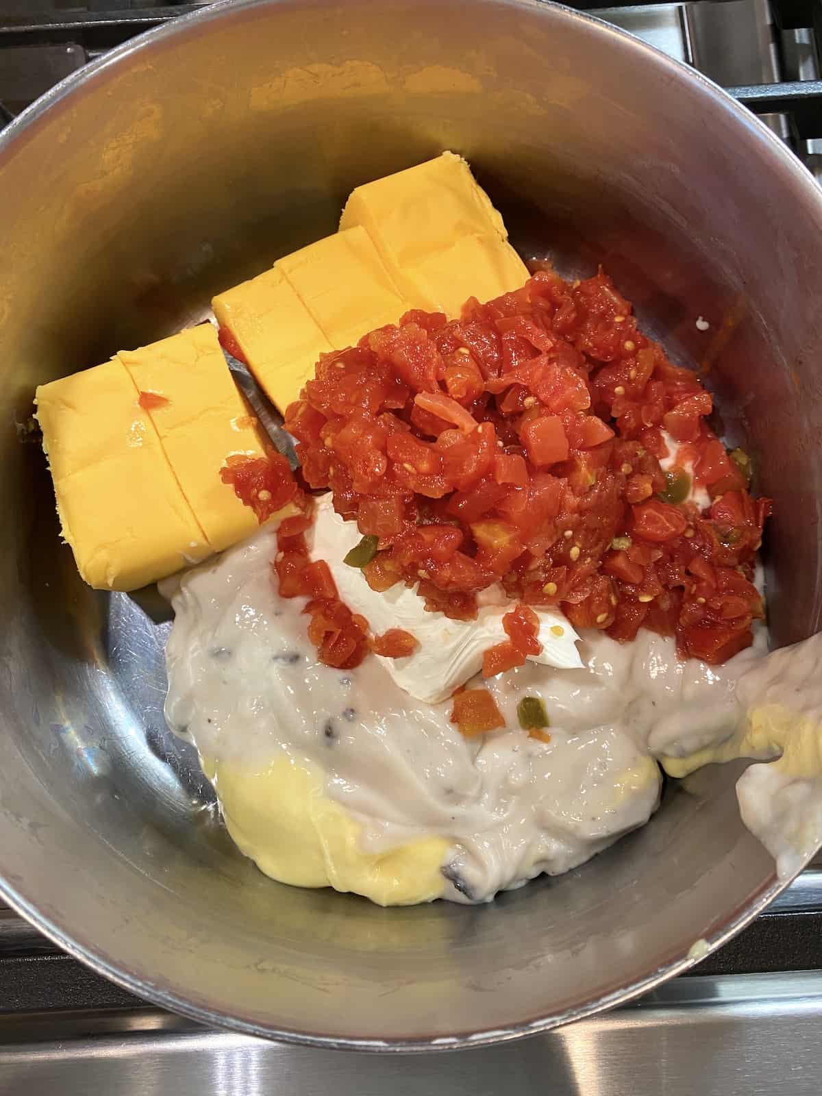 Velveeta, creamed soup, cream cheese and Rotel in a pot on the stove.