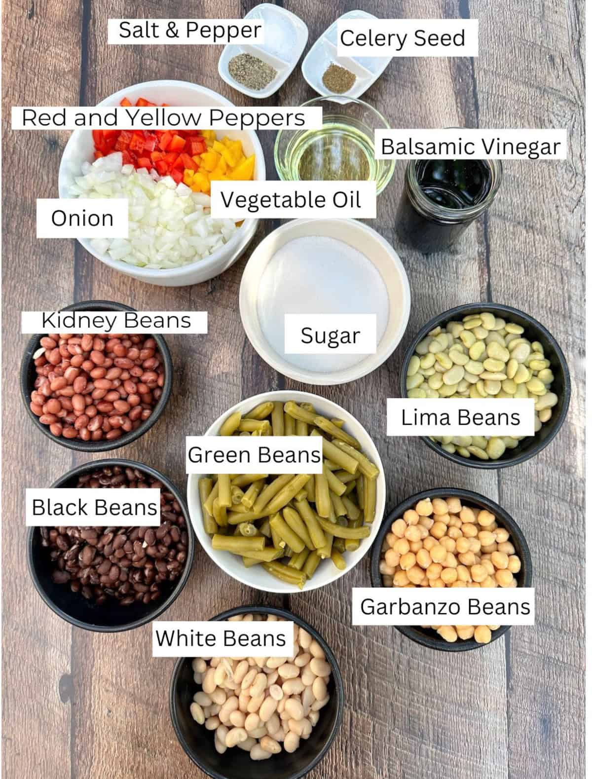 Cold Green Bean Salad ingredients arranged in individual bowls on a table with labels on each ingredient.