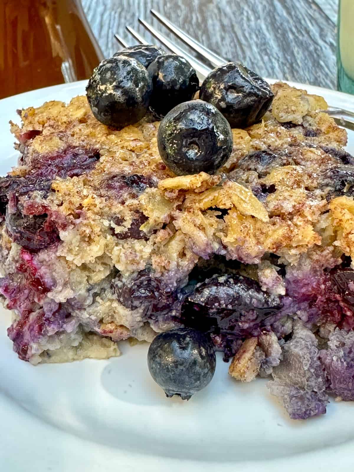 A close shot of a serving a blueberry baked oatmeal with berries on top and on the side.