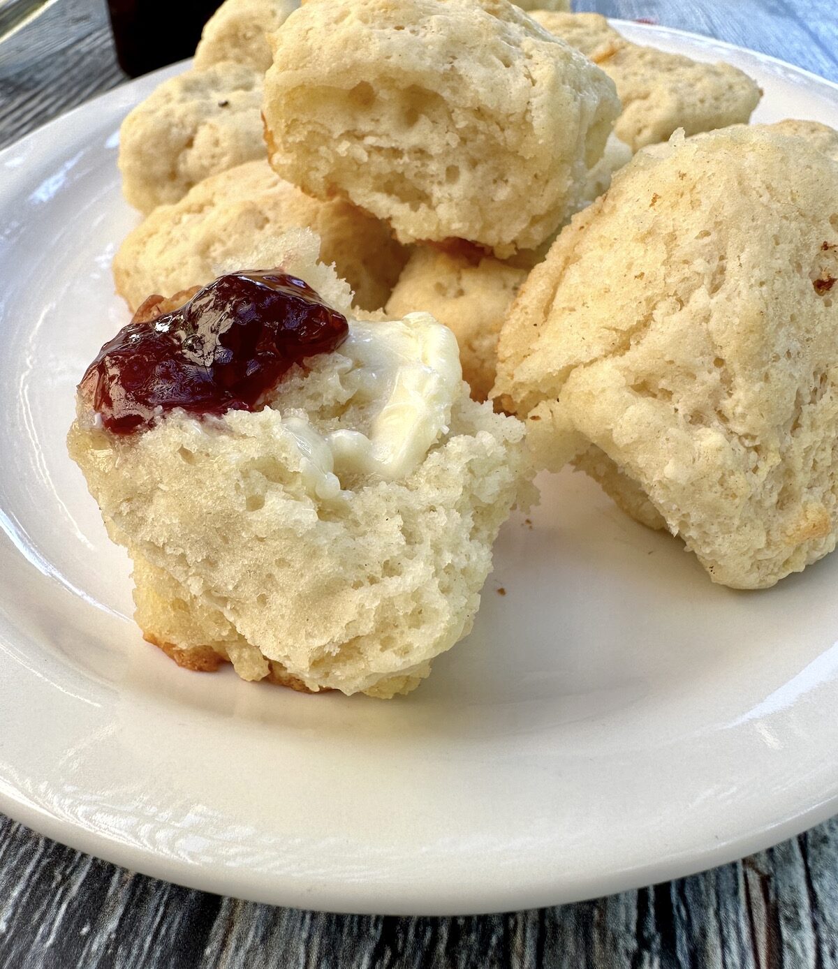 Biscuits on a plate, with one spread with jam and butter.