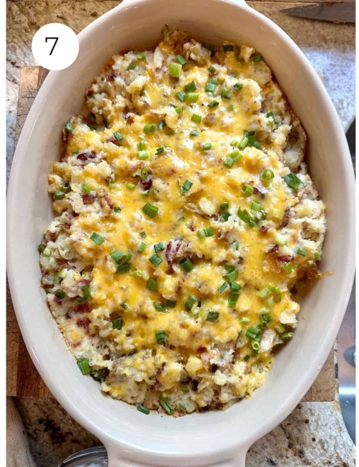 Baked, twice baked mashed potatoes in a casserole dish with melted cheese on top.