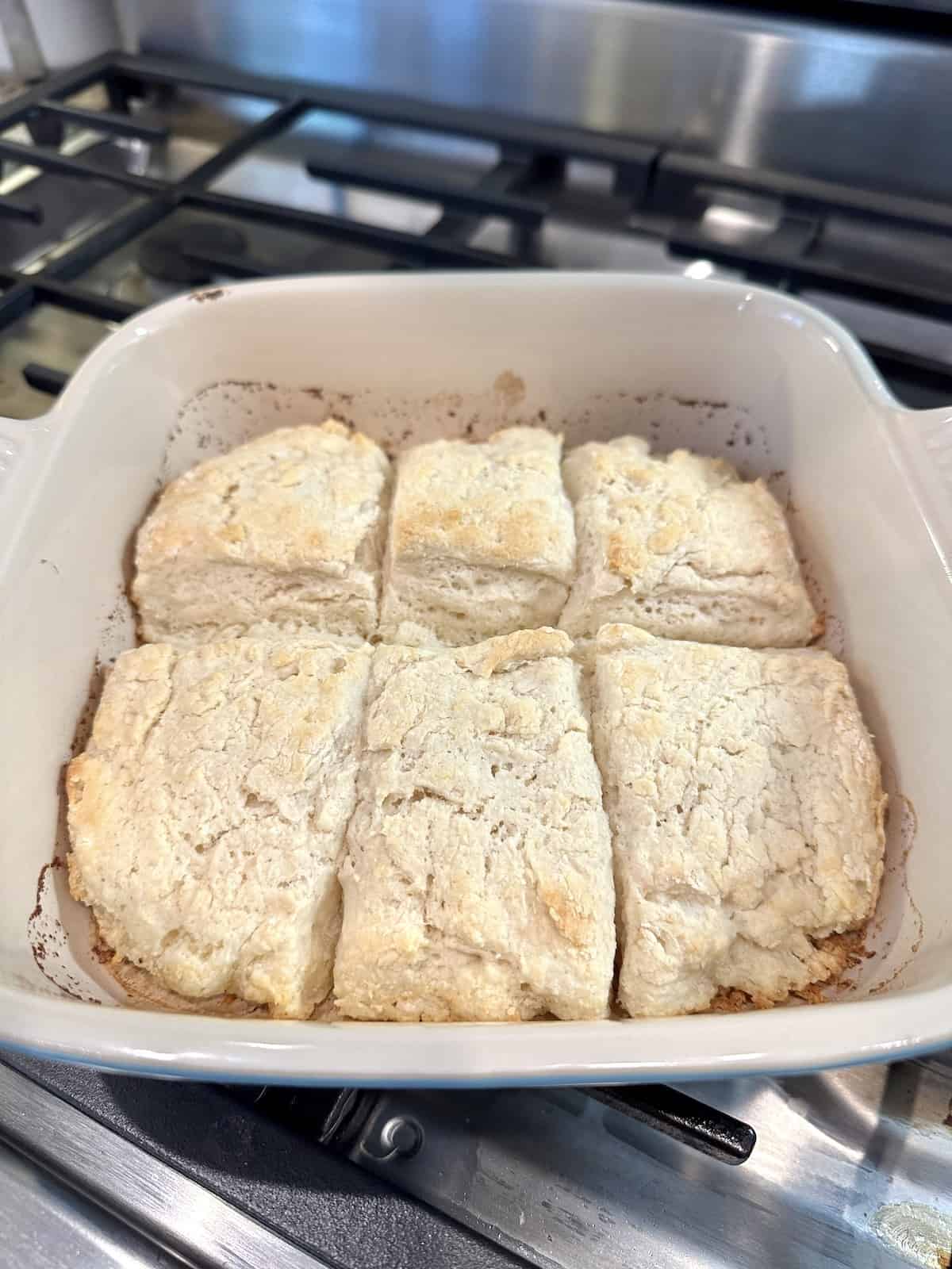 Baked biscuits in a small baking dish on the stovetop.