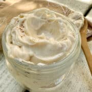 Honey butter in a small jar on a table with a wooden spoon on the side of the jar.