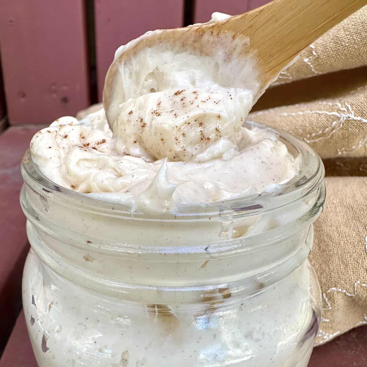 Whipped honey butter in a jar with a wooden spoon scooping out a serving.