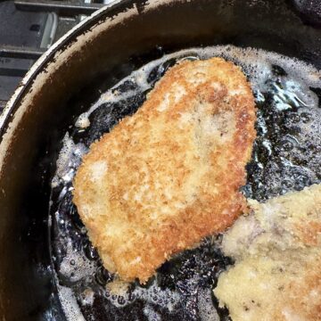 Chicken cutlets with panko breading in hot oil in a skilled on the stove.