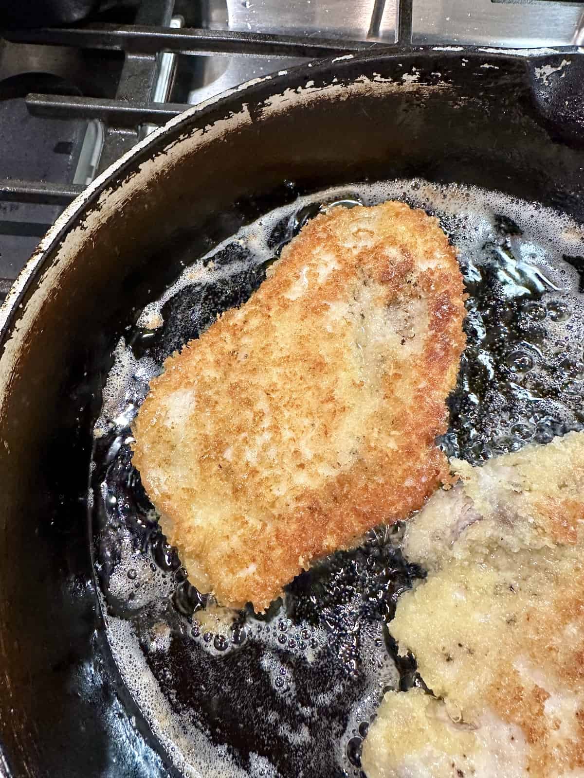 Chicken cutlets in hot oil in a skilled on the stove.