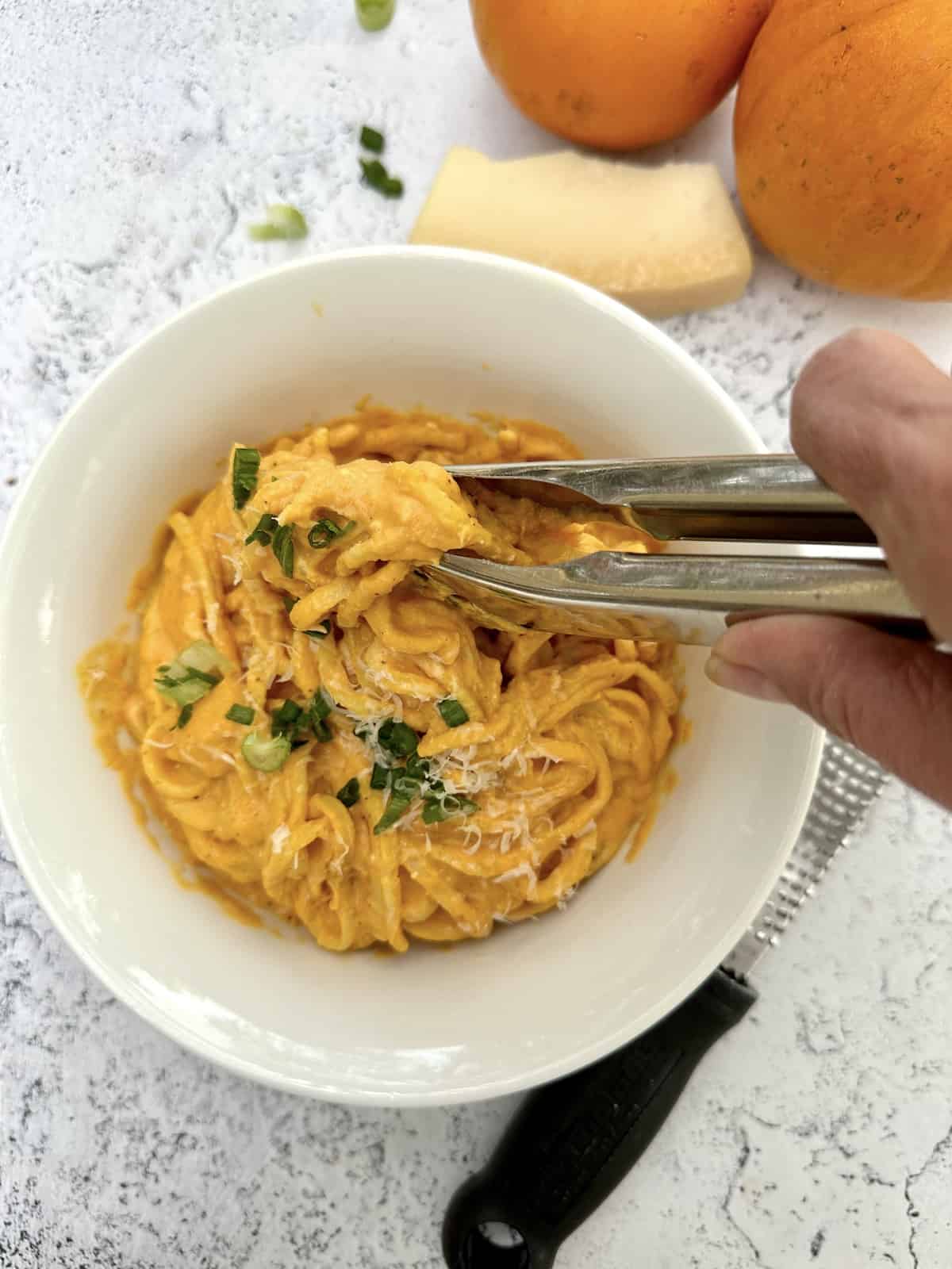 Tongs being used to scoop a serving of pasta.