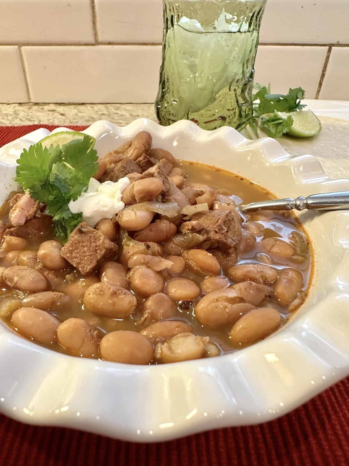 Pinto bean chili in a bowl with a glass of water on the side.