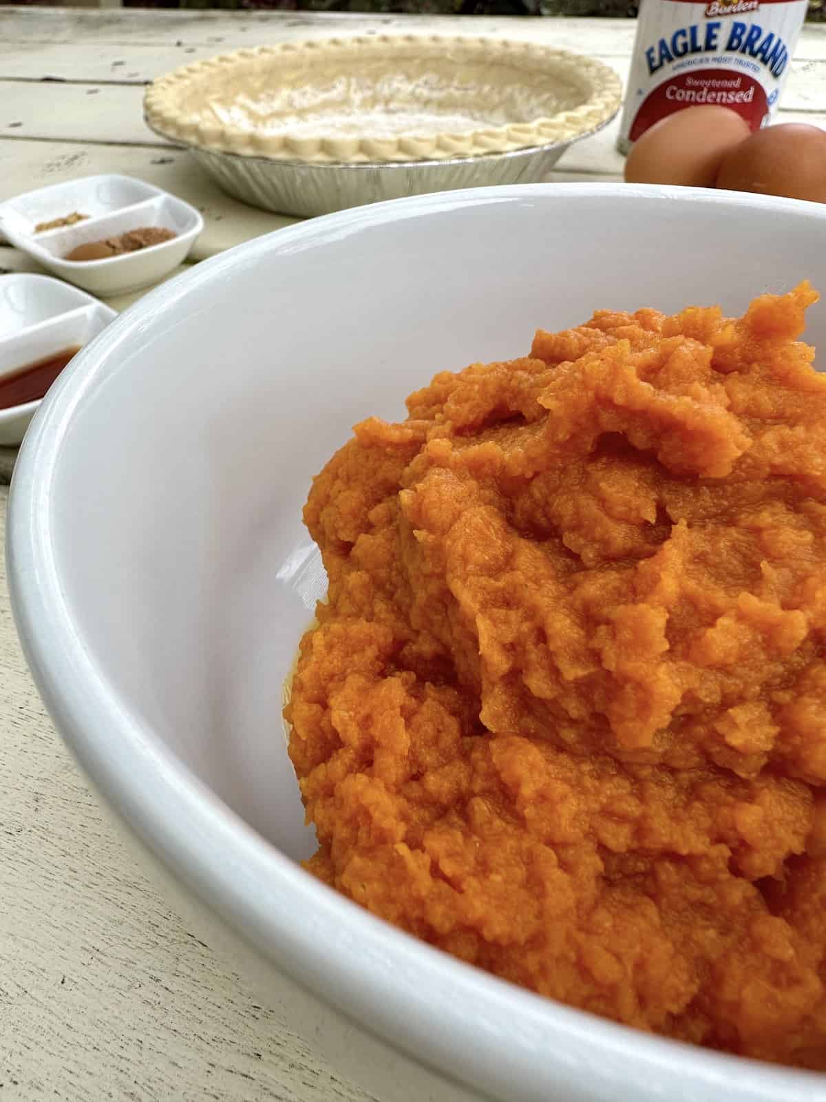 Pumpkin puree in a bowl with pie ingredients.