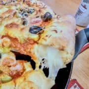 A serving a cheese-stuffed pizza being scooped up,