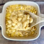 A large spoonful of smoked gouda mac and cheese held over a baking dish filled with the mac and cheese.