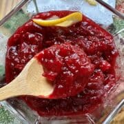 Cranberry orange sauce in a bowl with a spoon and a slice of orange.