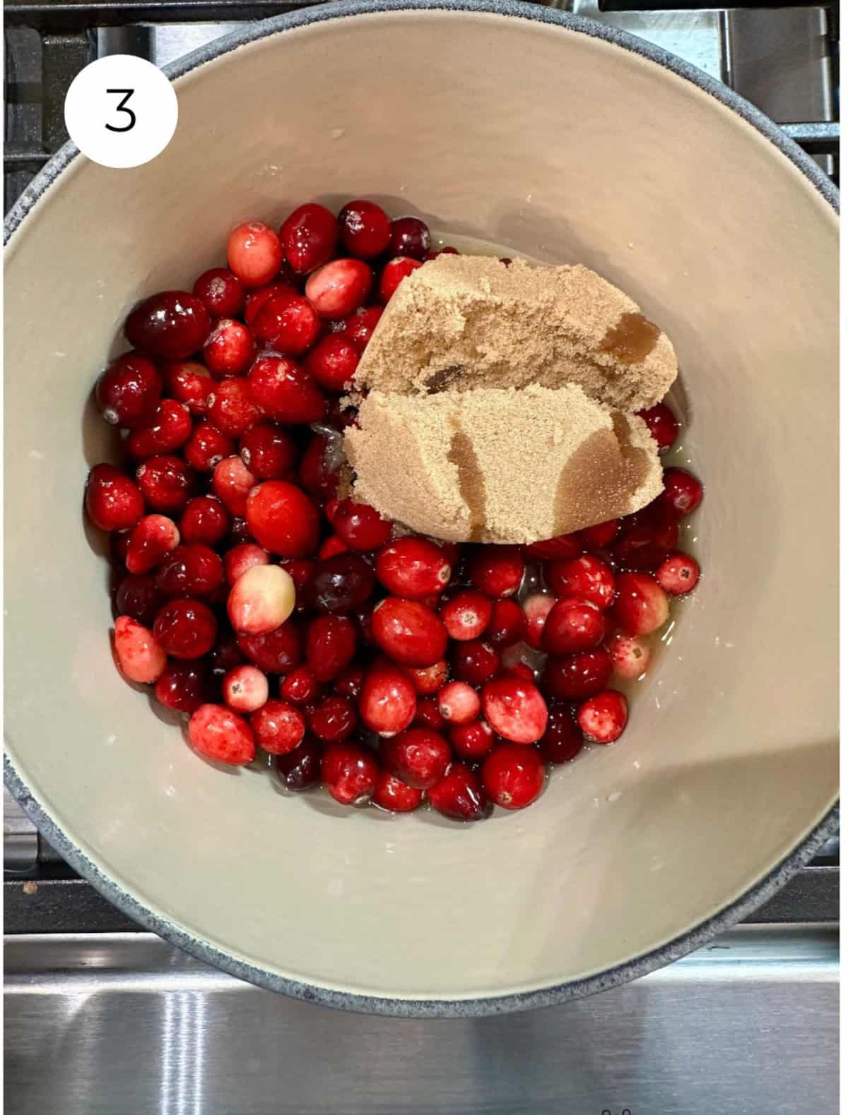 Fresh cranberries with brown sugar in a pan on the stove.