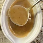 A gravy spoon in a serving bowl of gravy.