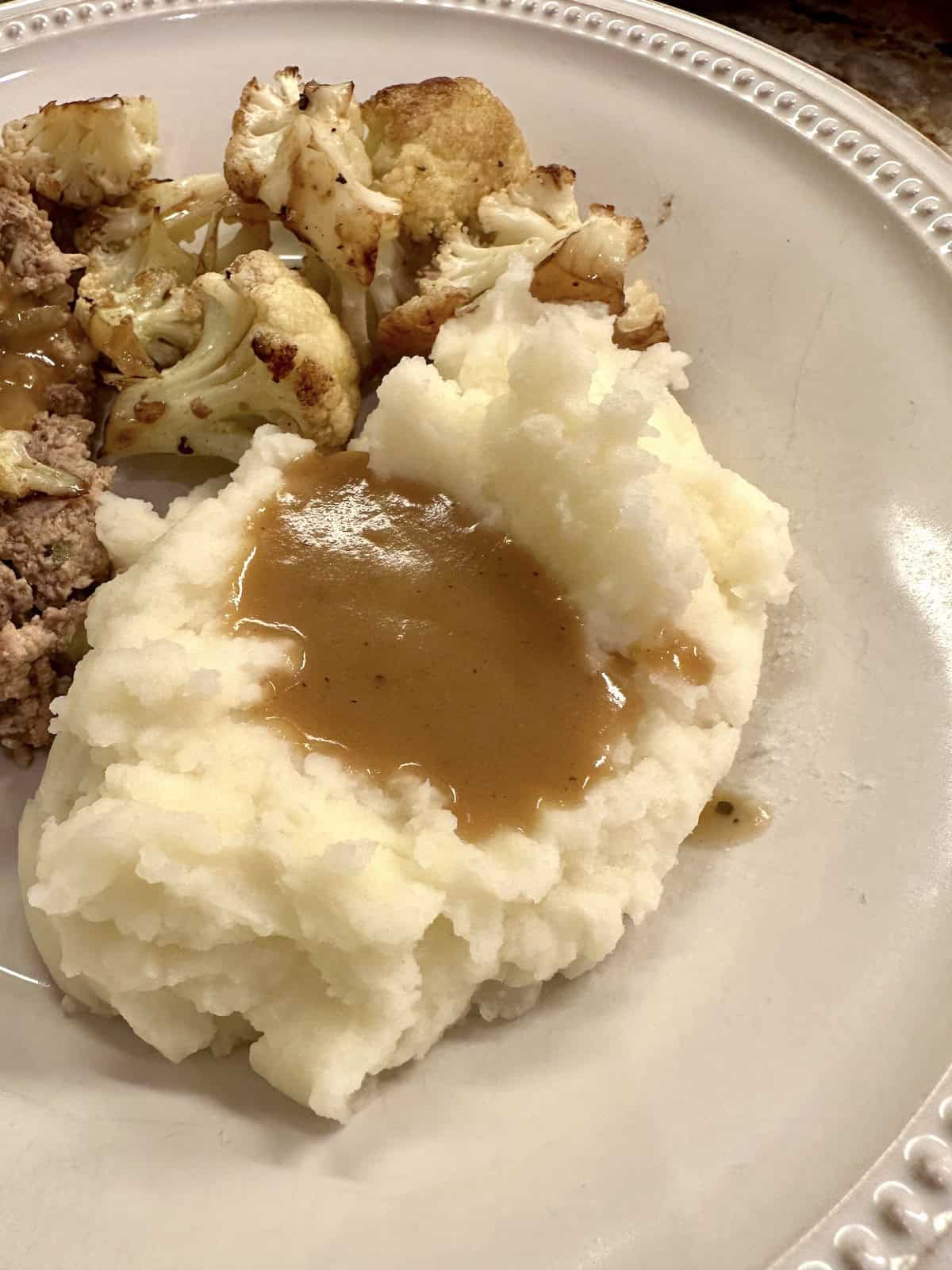 Gravy on mashed potatoes on a plate.