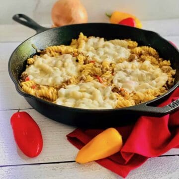 A skillet with pasta and melted cheese.