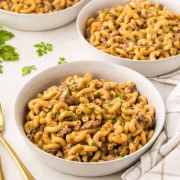 Pasta with ground beef in serving bowls with silverwave and napkins.