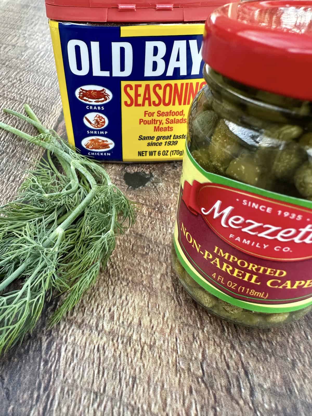 Dill, a container of Old Bay Seasoning and a jar of capers.