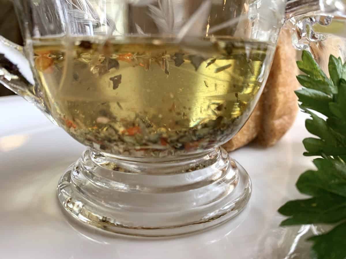 A small serving pitcher of oil oil with herbs.