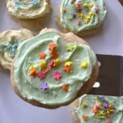 A frosted cookie on a spatula with more cookies on a plate.