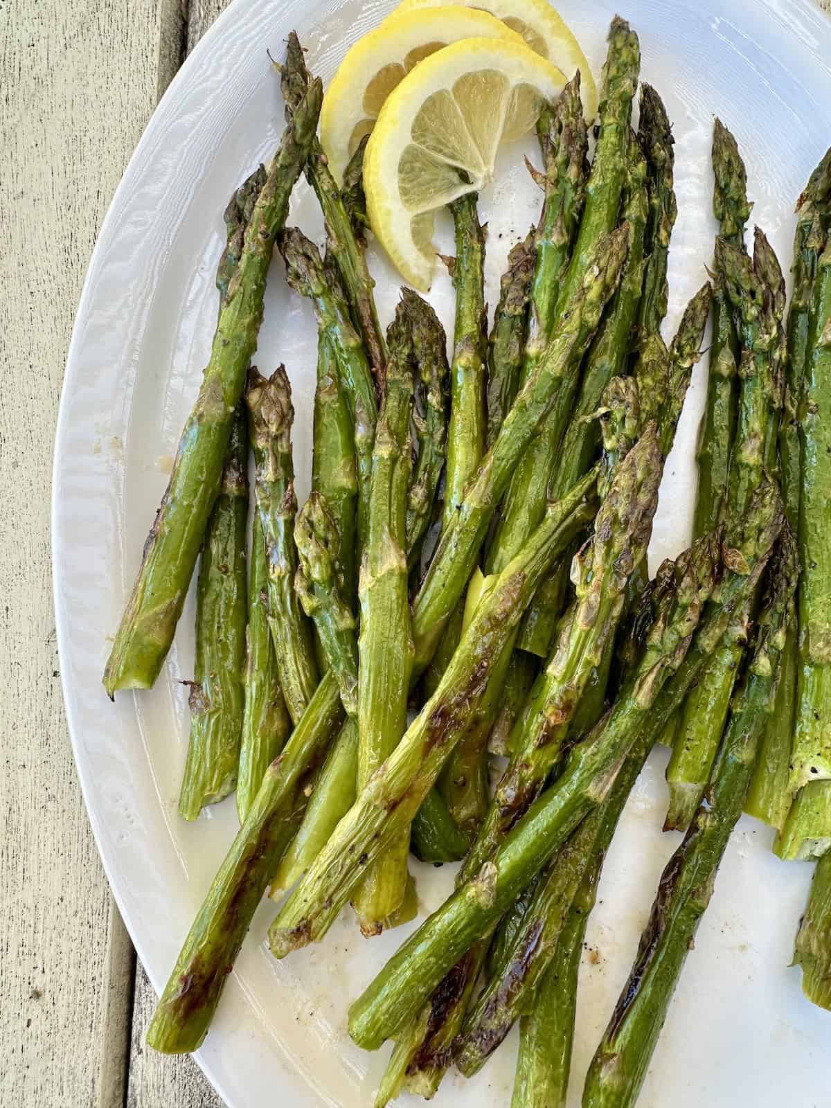 Pan roasted asparagus on a platter with lemon.