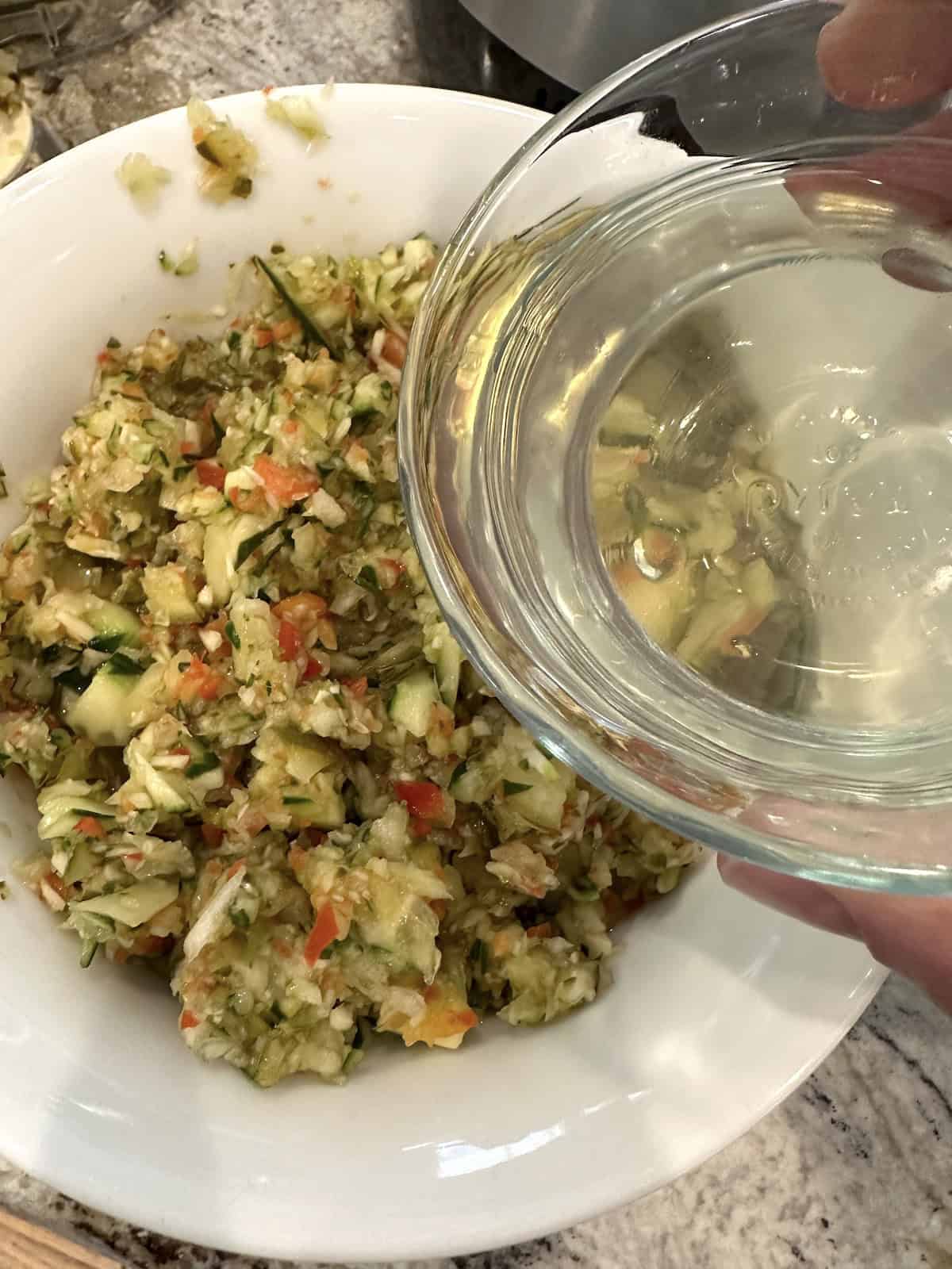 Pickle de gallo ingredients in a bowl with a small bowl of vinegar.