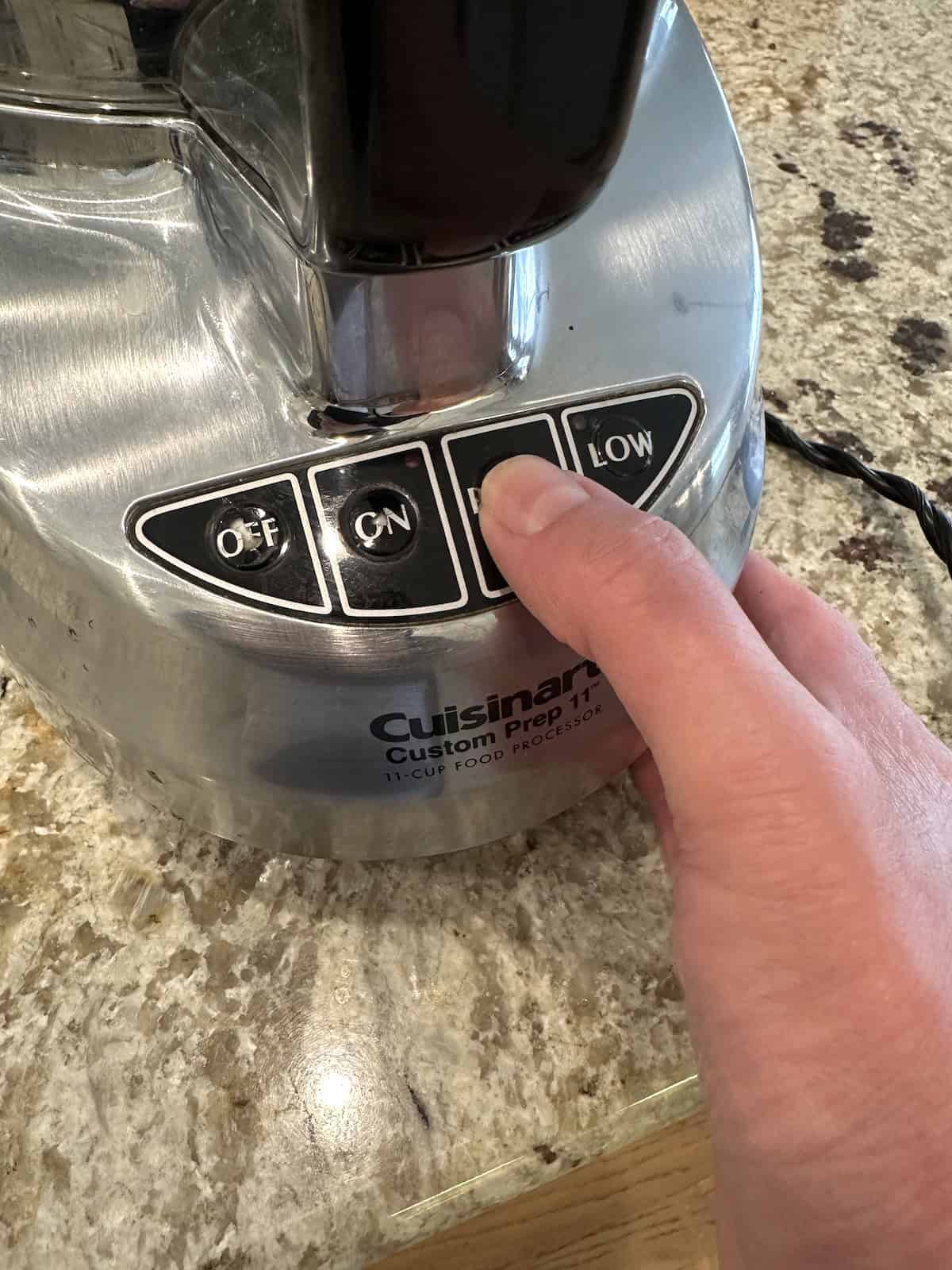 A hand on the base of a food processor.