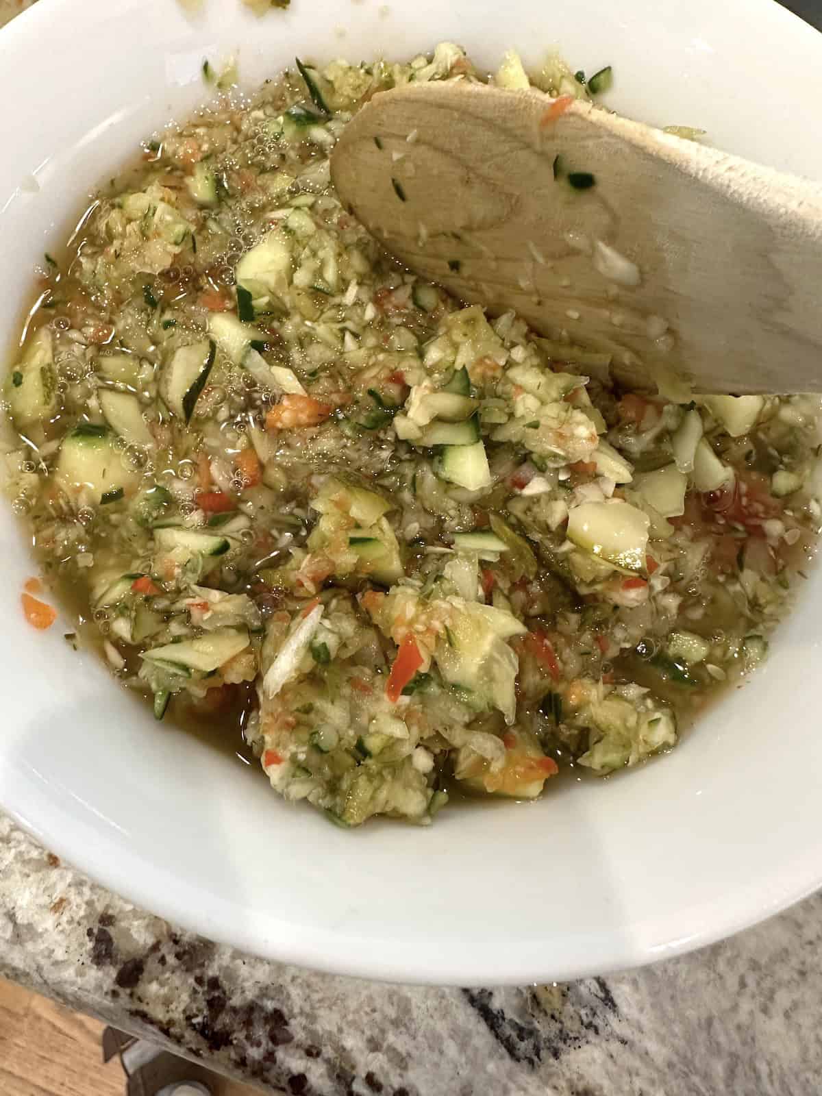 A spoon stirring pickle de gallo in a bowl.