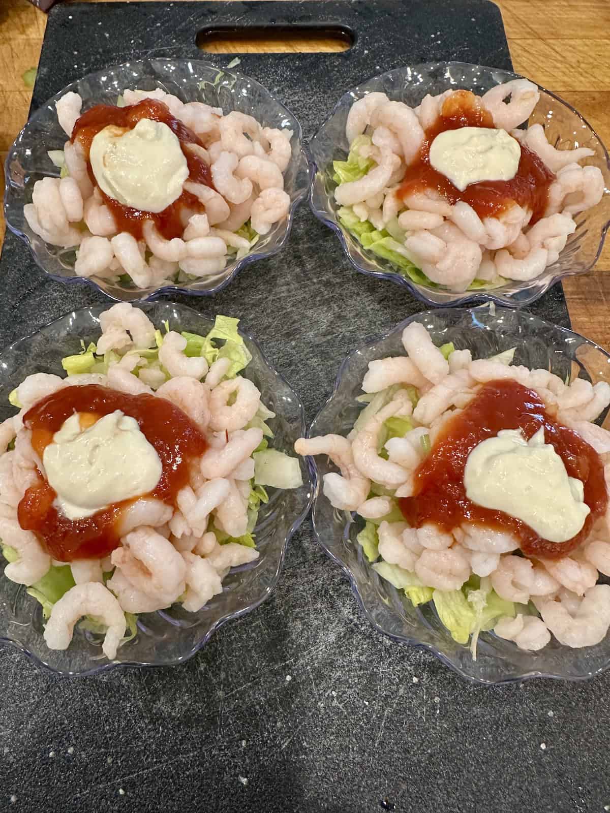 Shrimp in small cups with lettuce, celery, cocktail sauce and horseradish sauce.