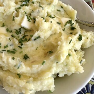 Yukon gold mashed potatoes with butter and chives in a bowl.