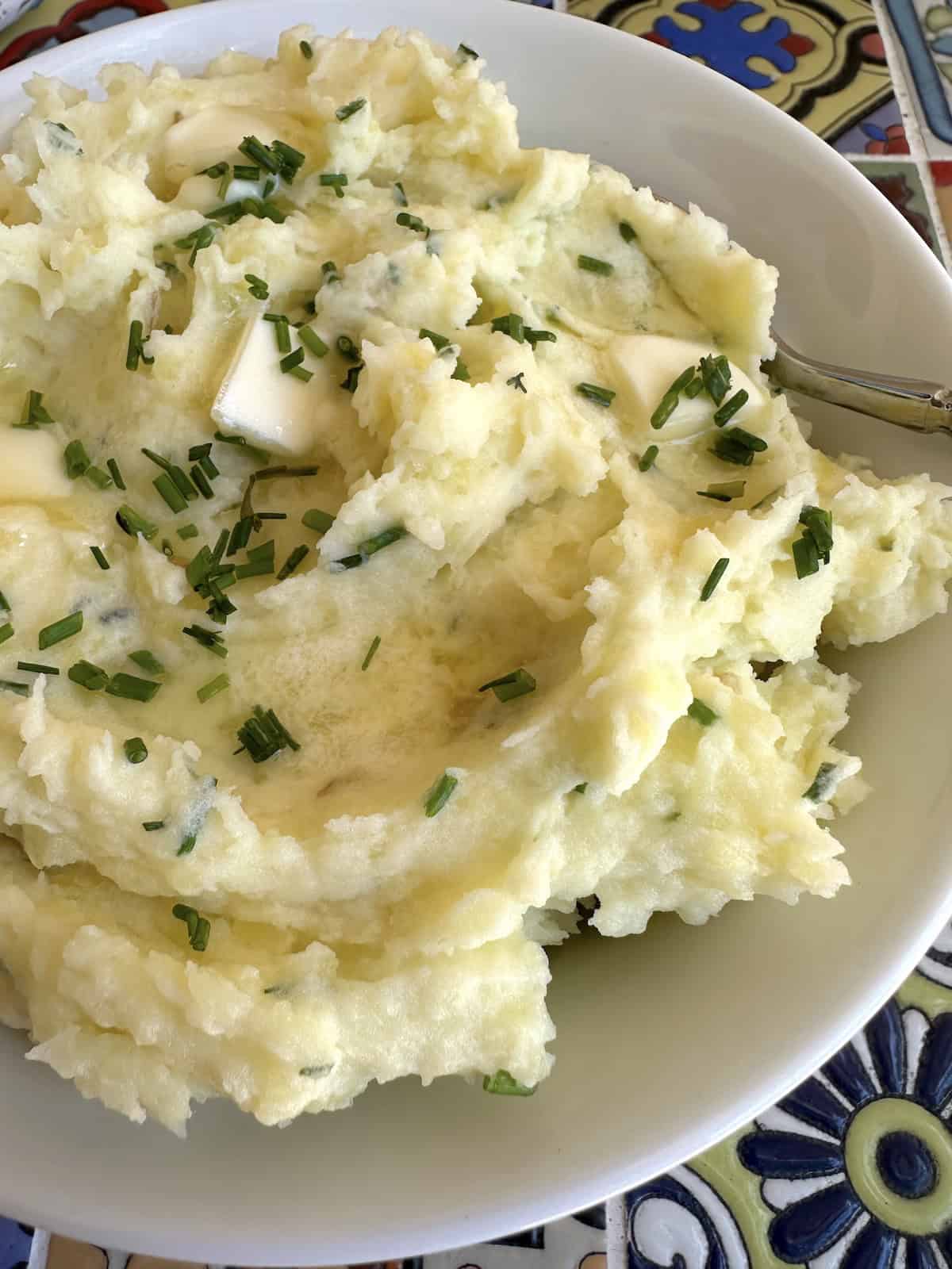 Yukon gold mashed potatoes with butter and chives in a bowl.