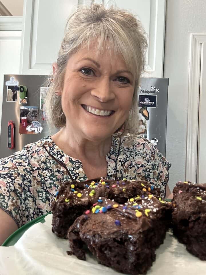 Melinda in the kitchen holding a plate of chocolate cake slices.