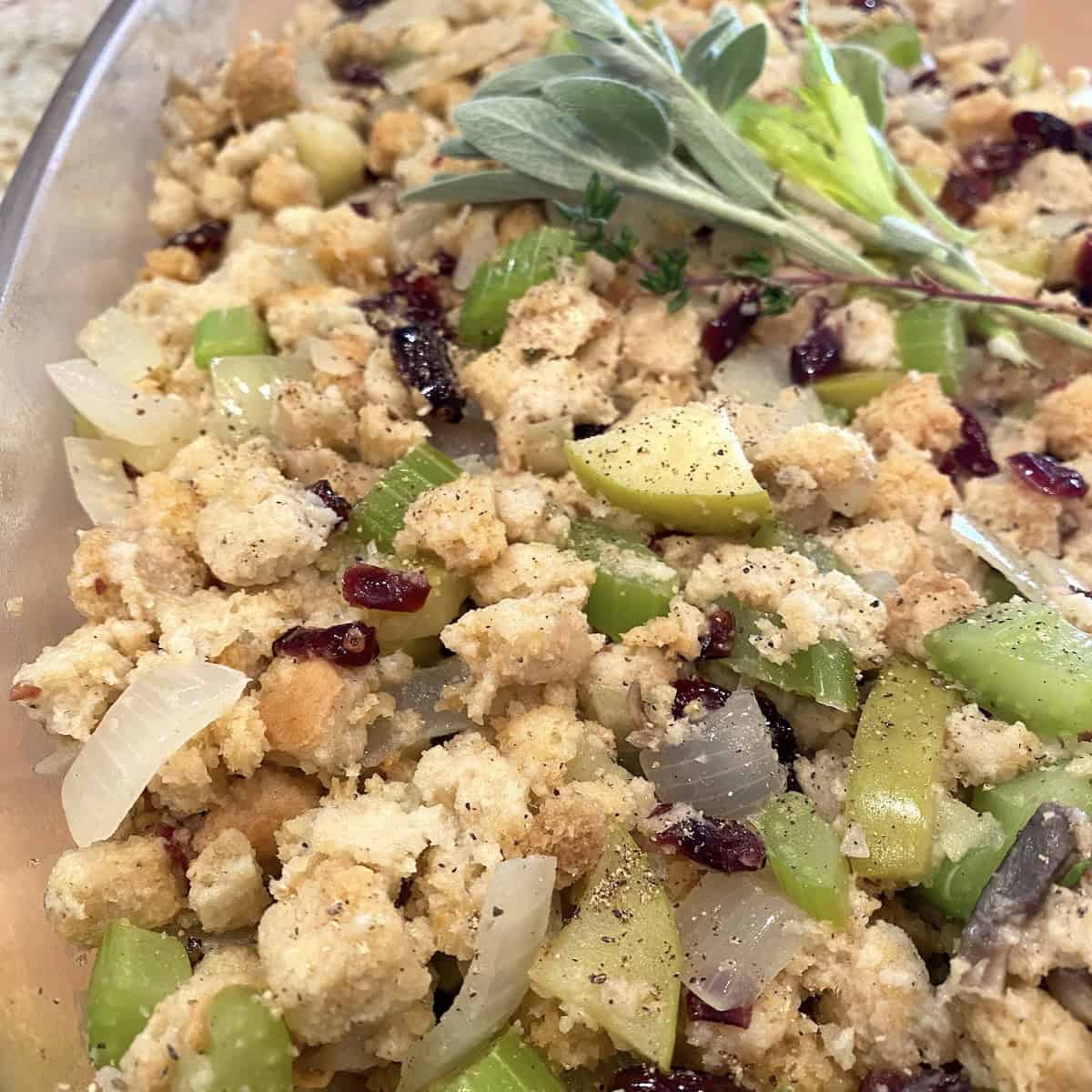 A dish with stuffing, apples, craisins and celery.