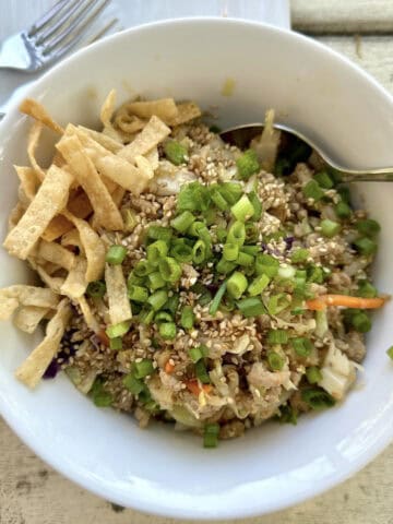 A serving of spring roll in a bowl on a table outdoors with two forks and a plate.