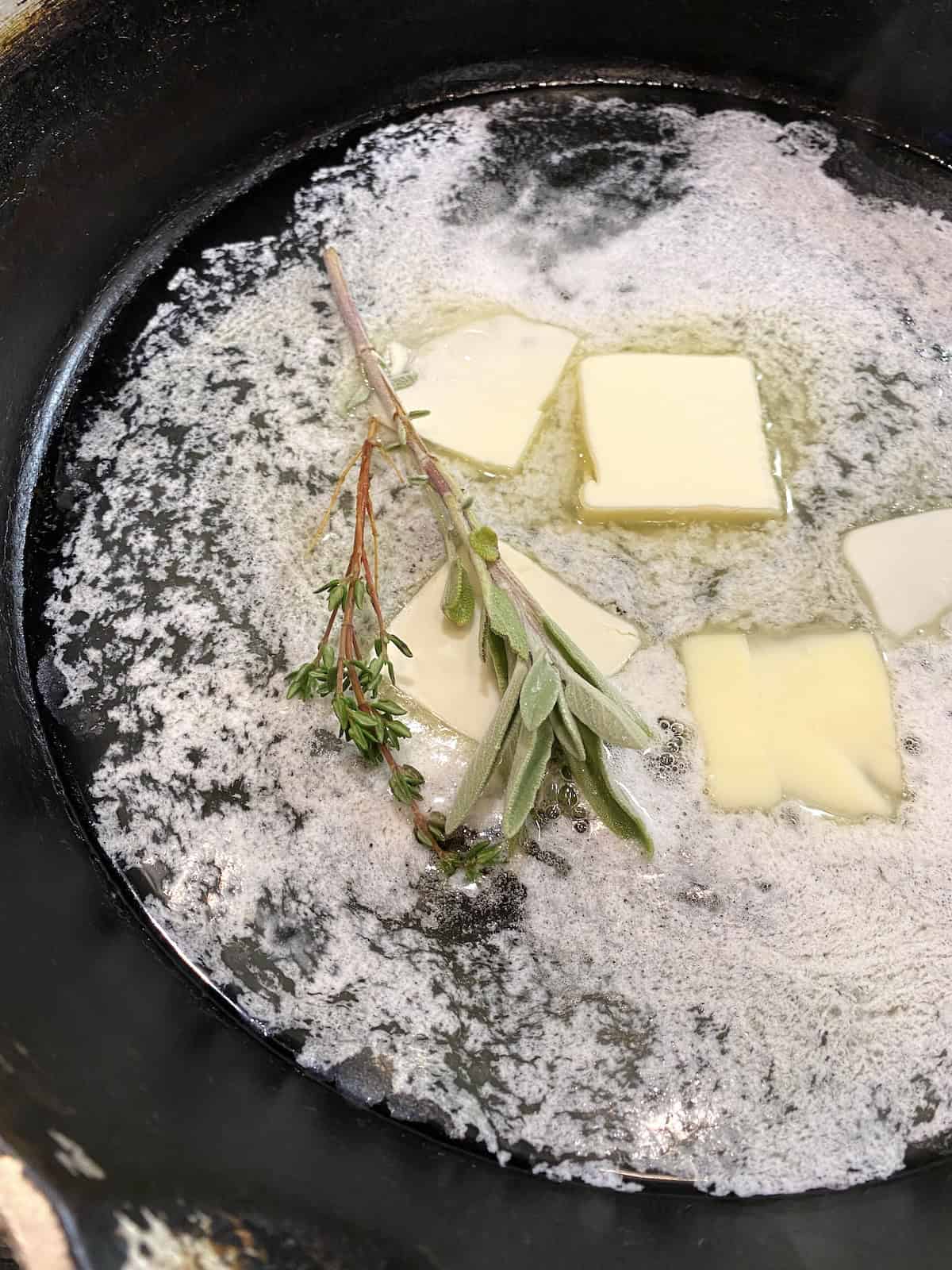 Butter and herbs in a frying pan.